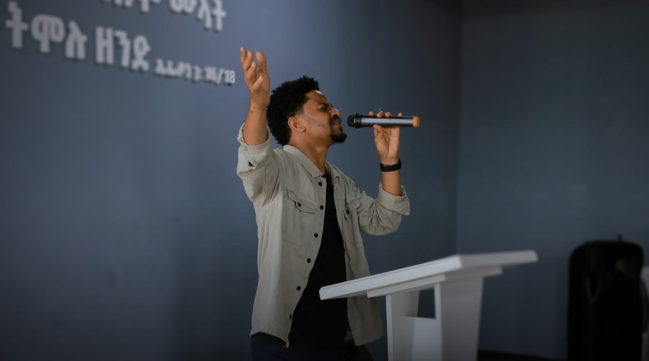 A worship leader singing with his hand raised
